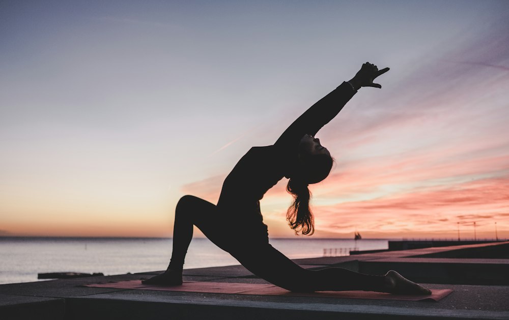 Woman practicing yoga at sunrise for holistic health and longevity